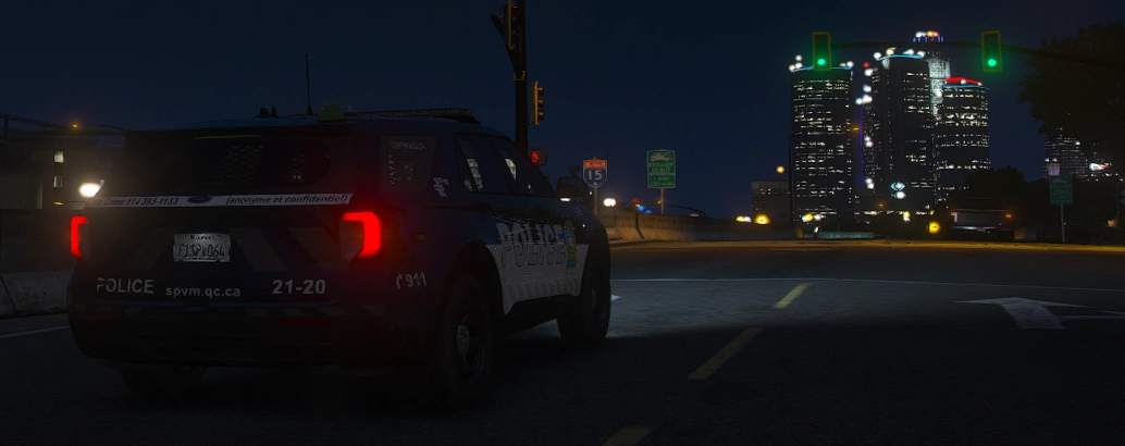 Un VUS de la Police de Montréal la nuit, l'autoroute 15 et les tours du centre-ville au fond